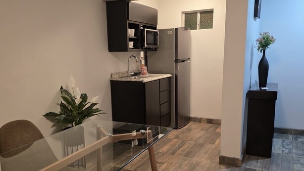 A modern kitchen with a glass dining table, dark cabinetry, and a microwave.