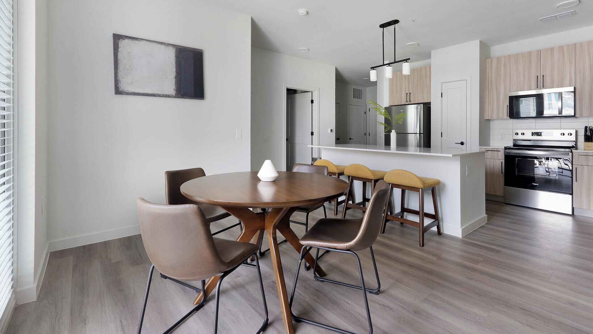 A modern kitchen with a central island, stainless steel appliances, and a dining area with a round table and chairs.