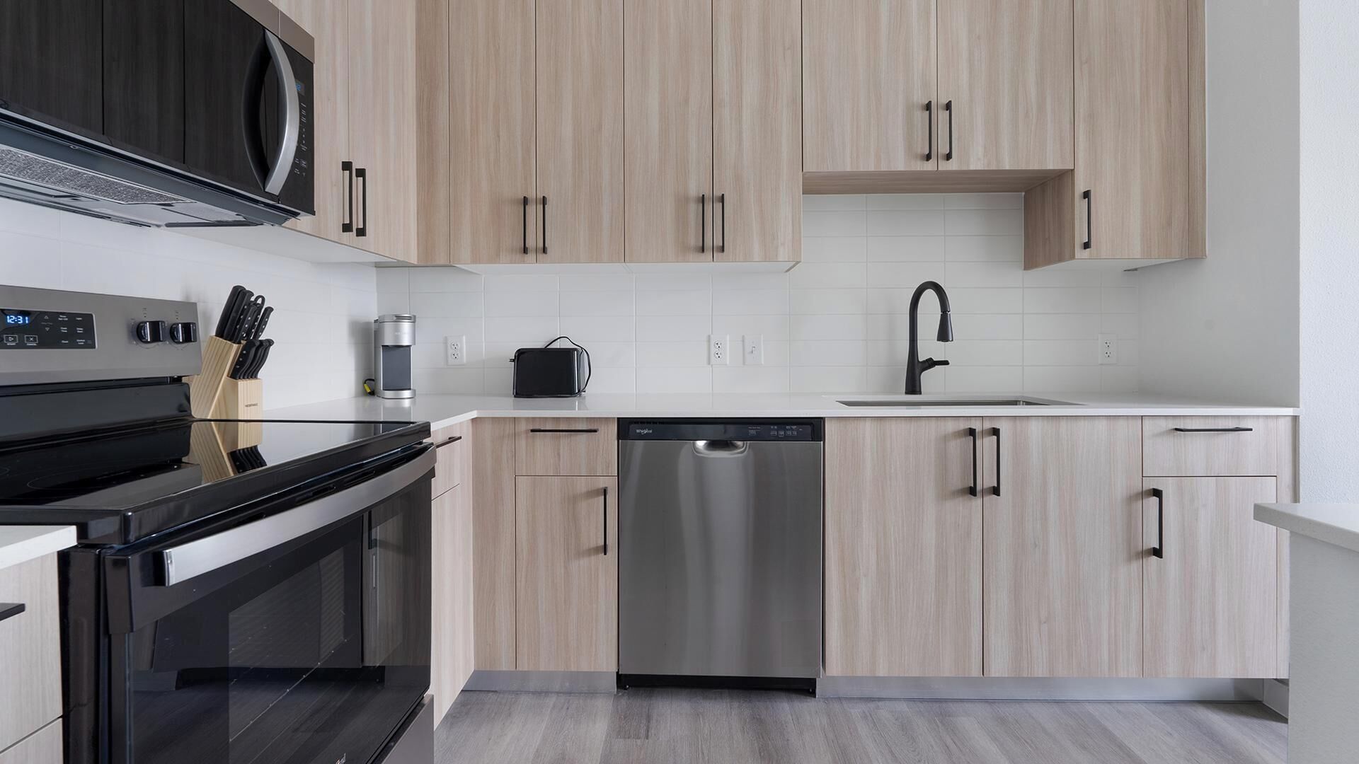 A modern kitchen with a dishwasher, stove, and microwave.