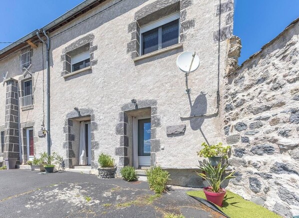 Un edificio in pietra con diverse finestre e porte, piante in vaso e un'antenna parabolica.