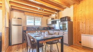 Uma cozinha com piso de madeira, uma mesa de jantar com cadeiras, geladeira, micro-ondas, forno e armários.