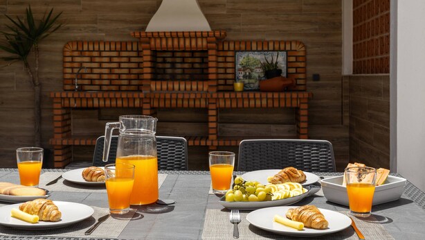 Colazione all'aperto con forno a mattoni, piatti di cibo e bicchieri di succo d'arancia.