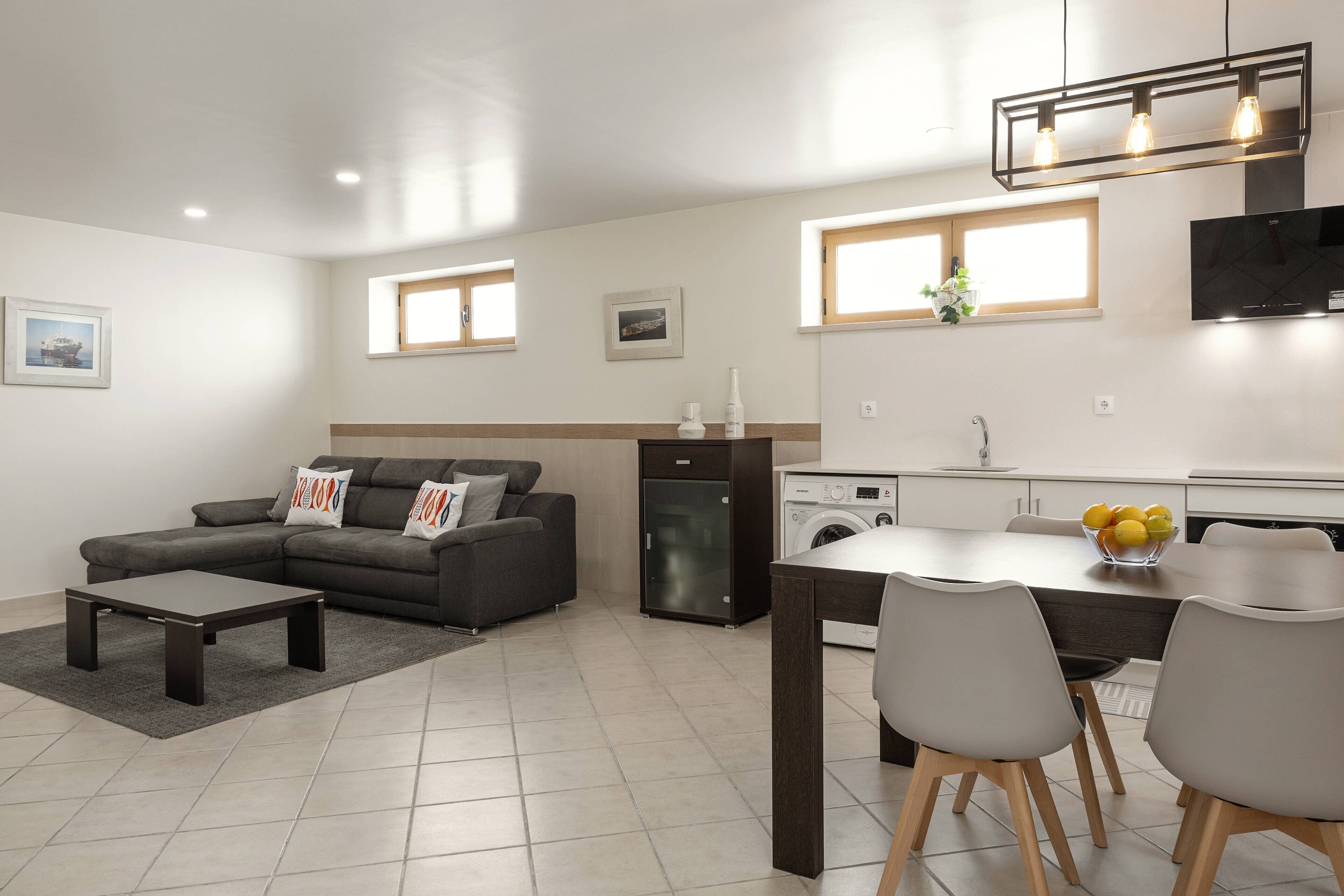 Ein modernes Wohnzimmer mit Sofa, Couchtisch und einem Essbereich mit Stühlen und Tisch.