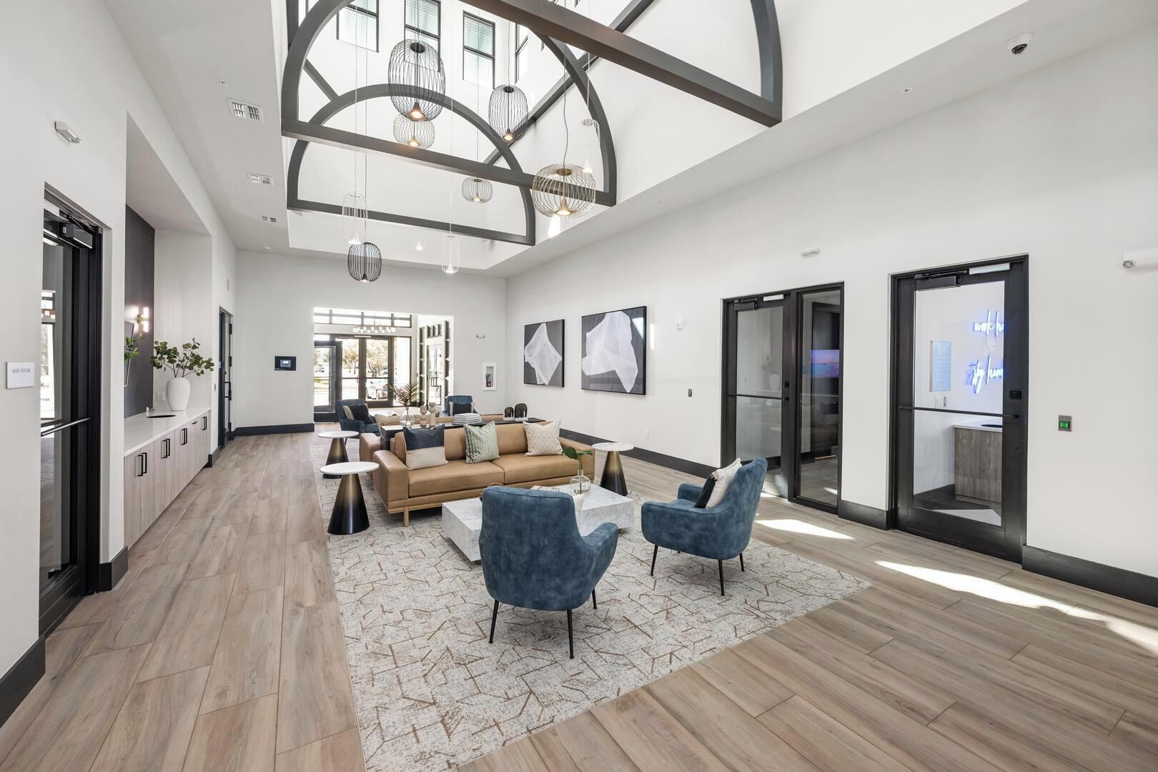 A spacious hotel lobby with a high ceiling, modern furniture, and a large window providing natural light.