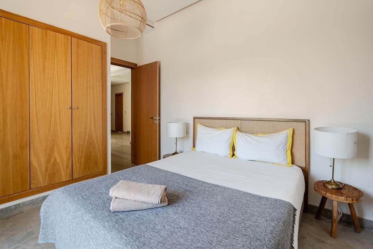 Une chambre à coucher comprenant un lit, deux lampes de chevet, une table de chevet, une armoire et une porte donnant sur une autre pièce.
