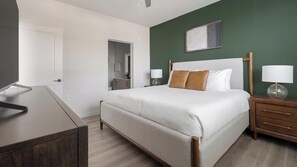A neatly arranged hotel room with a bed, bedside tables, a TV, and a bathroom visible through an open door. - Landing | Stylish 2BD, Gym, Clubhouse (North Fort Myers)