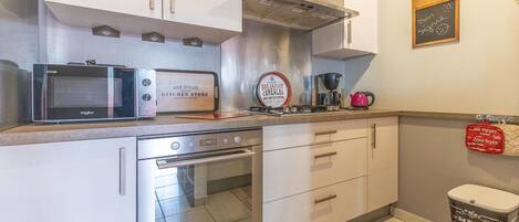 Una cocina moderna con microondas, tostadora, cafetera y una pizarra con un mensaje.