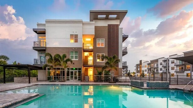 Un edificio moderno de varios pisos con una piscina delantera.