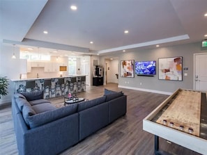 Ein moderner Lounge-Bereich mit einer Couch, einem Tischtennis-Tisch und einer Küche im Hintergrund.