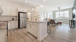 Una cocina moderna con electrodomésticos de acero inoxidable, armarios de madera clara y una isla central.