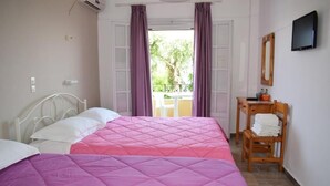 A bedroom with two beds, a wooden chair, a small table with toiletries, and a TV on the wall. - Rising Sun Apartments Studios (Corfu)