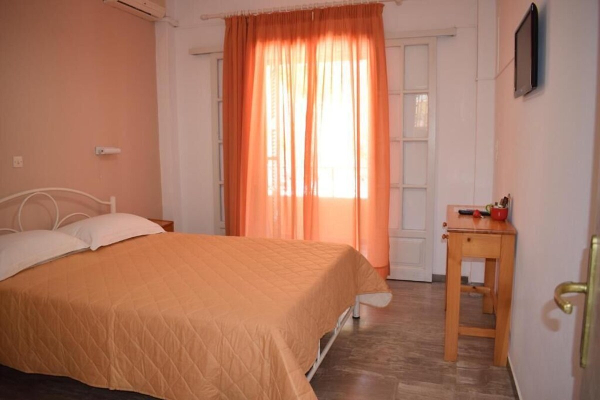 Ein Schlafzimmer mit Bett, Nachttisch, Holztisch und einer Tür.