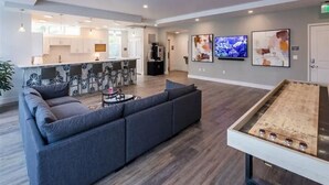 Ein moderner Lounge-Bereich mit einer Couch, einem Tischtennis-Tisch und einer Küche im Hintergrund.