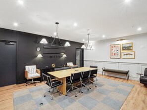 A modern meeting room with a long table, chairs, and pendant lighting. - Landing | Spectacular 1BD, Courtyard, Pool (Richmond)