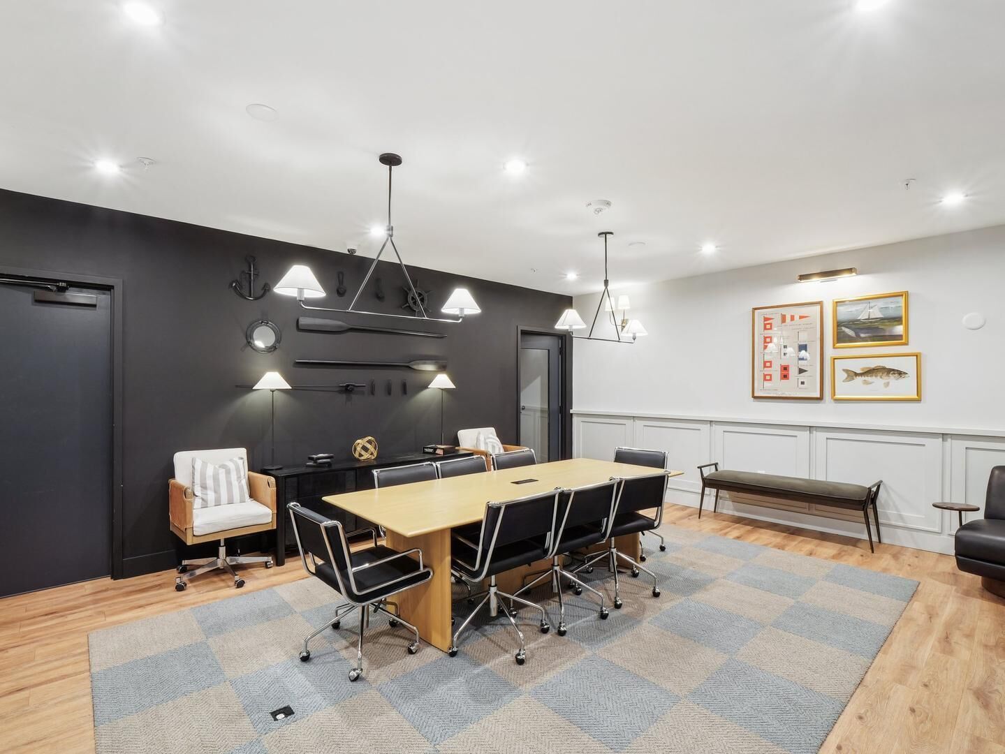 Uma sala de reunião moderna com uma mesa comprida, cadeiras e iluminação pendente.