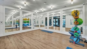 A gym with mirrored walls, wooden floors, and exercise equipment. - Landing | Incredible 2BD, Pool, Courtyard (Richmond)
