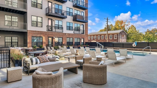 Area piscina sul tetto con poltronne, un tavolo e un piccolo angolo bar.