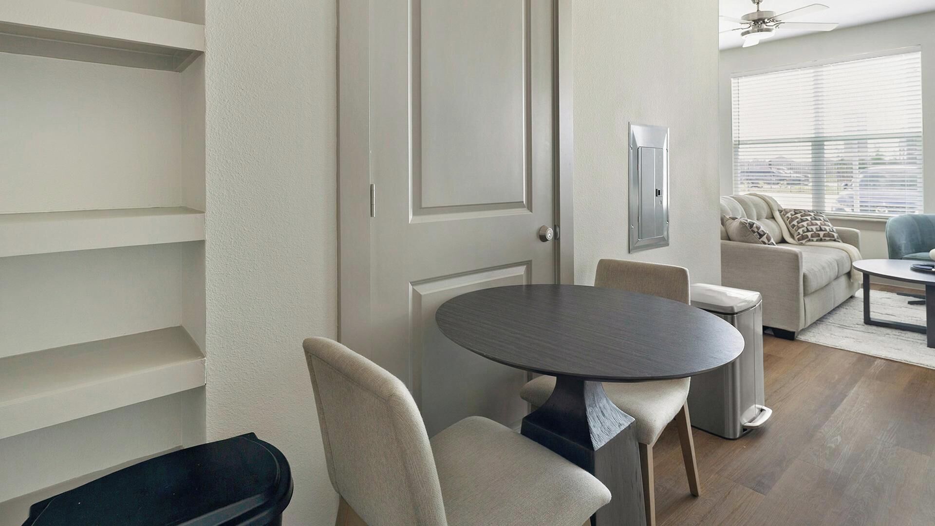 Uma sala de estar moderna com área de jantar, um conjunto de sofás e um ventilador de teto.