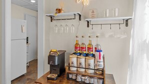 Ett köksutrymme med en kaffestation, inklusive Torani-sirap, en kaffebryggare och en skylt med texten ”MEN FÖRST KAFFE”.