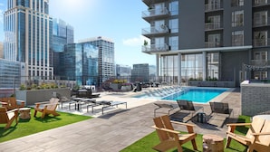 Un espace piscine aménagé sur le toit, avec des chaises longues, un jacuzzi et une vue sur les immeubles environnants.