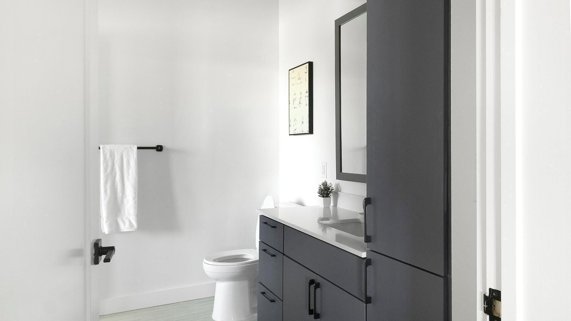 A modern bathroom with a toilet, a sink with a mirror, and a towel rack.
