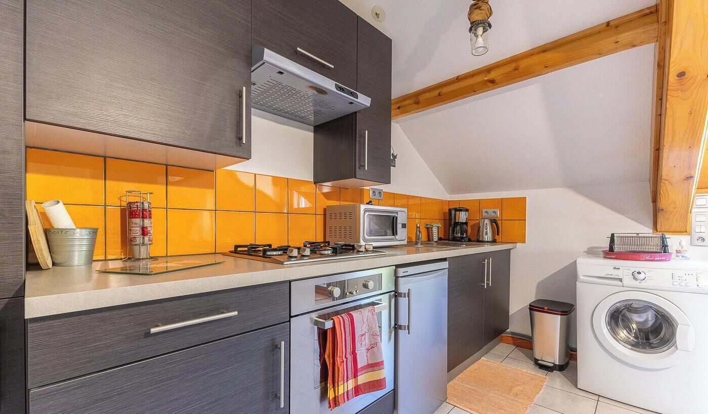 Una cocina funcional con estufa a gas, microondas y lavadora.