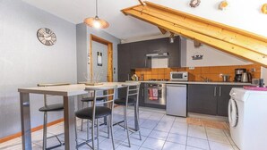 Keittiössä on ruokailutila, pyykinpesukone ja seinällä oleva kello.