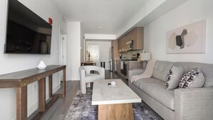 Ein modernes Wohnzimmer mit einer Couch, einem Couchtisch und einem an der Wand befestigten Fernseher.