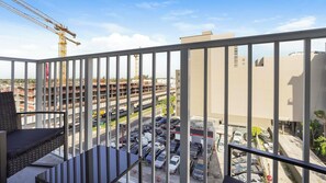 Ein Balkon mit Blick auf einen Parkplatz und Baukräne im Hintergrund.