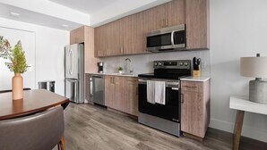 Eine moderne Küche mit Holzschränken, Edelstahlgeräten und einem Essbereich mit Holztisch und -stühlen.