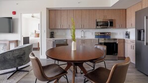 Eine moderne Küche mit Holzausstattung, Edelstahlgeräten und einer Essecke mit rundem Tisch und Ledersesseln.