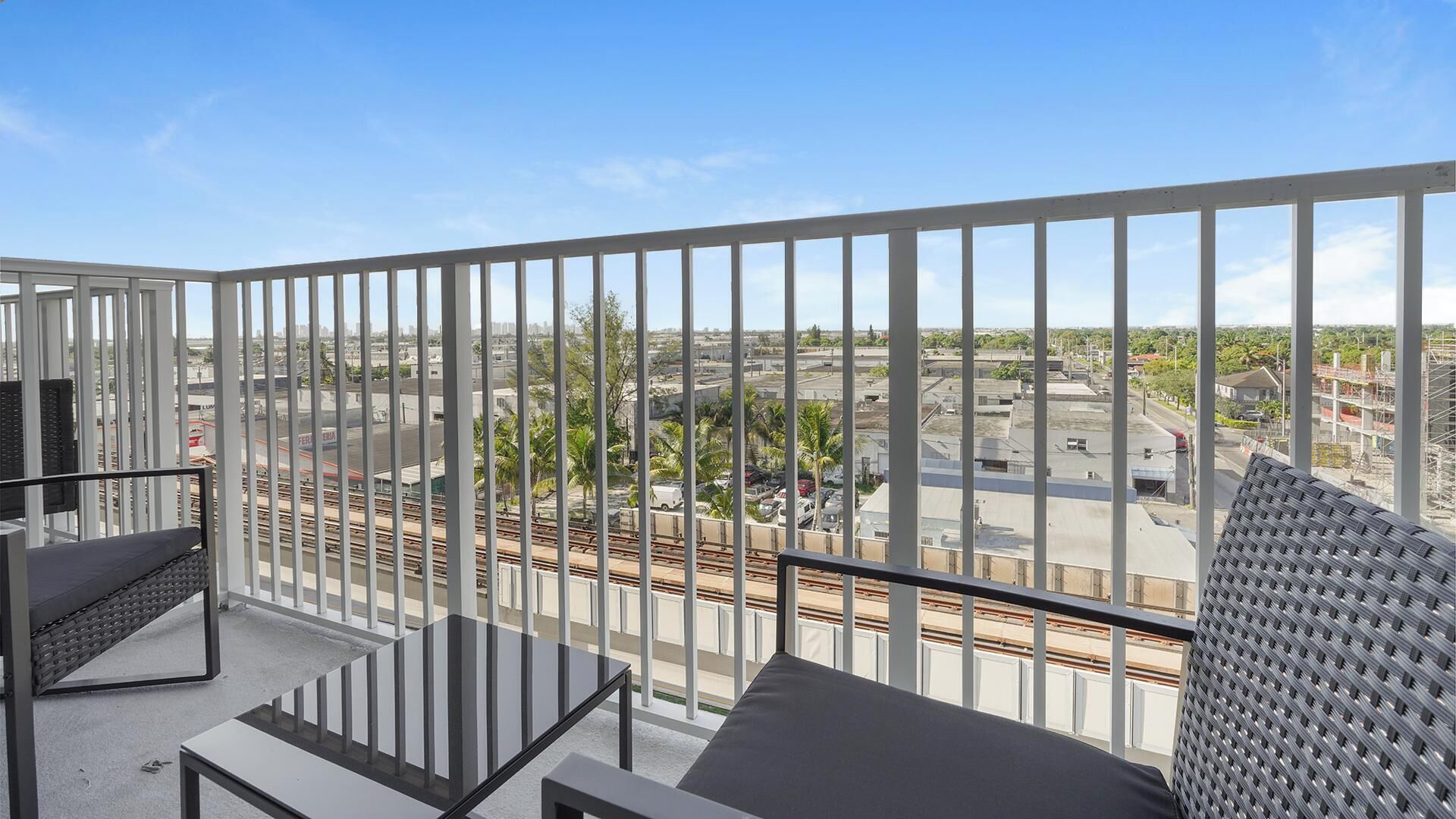 Un balcon offrant une vue sur le paysage urbain, avec des bâtiments et une voie ferrée.