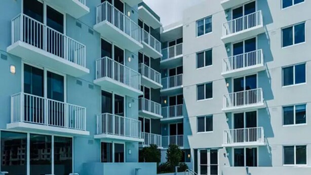Un bâtiment moderne doté d’une piscine, de nombreux balcons et de chaises longues.