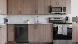 Une cuisine moderne avec des meubles en bois, un lave-vaisselle en acier inoxydable, un four à micro-ondes et un four traditionnel.