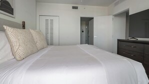 Une chambre à coucher comprenant un lit, une commode, un miroir et une porte donnant sur une autre pièce.