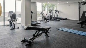 Ett gym med träningsutrustning, stora fönster och utsikt över omgivningarna.