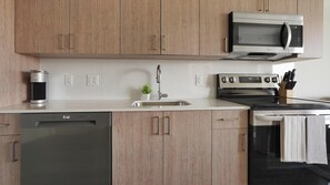 A modern kitchen with wooden cabinets, a stainless steel dishwasher, an oven, and a microwave.
