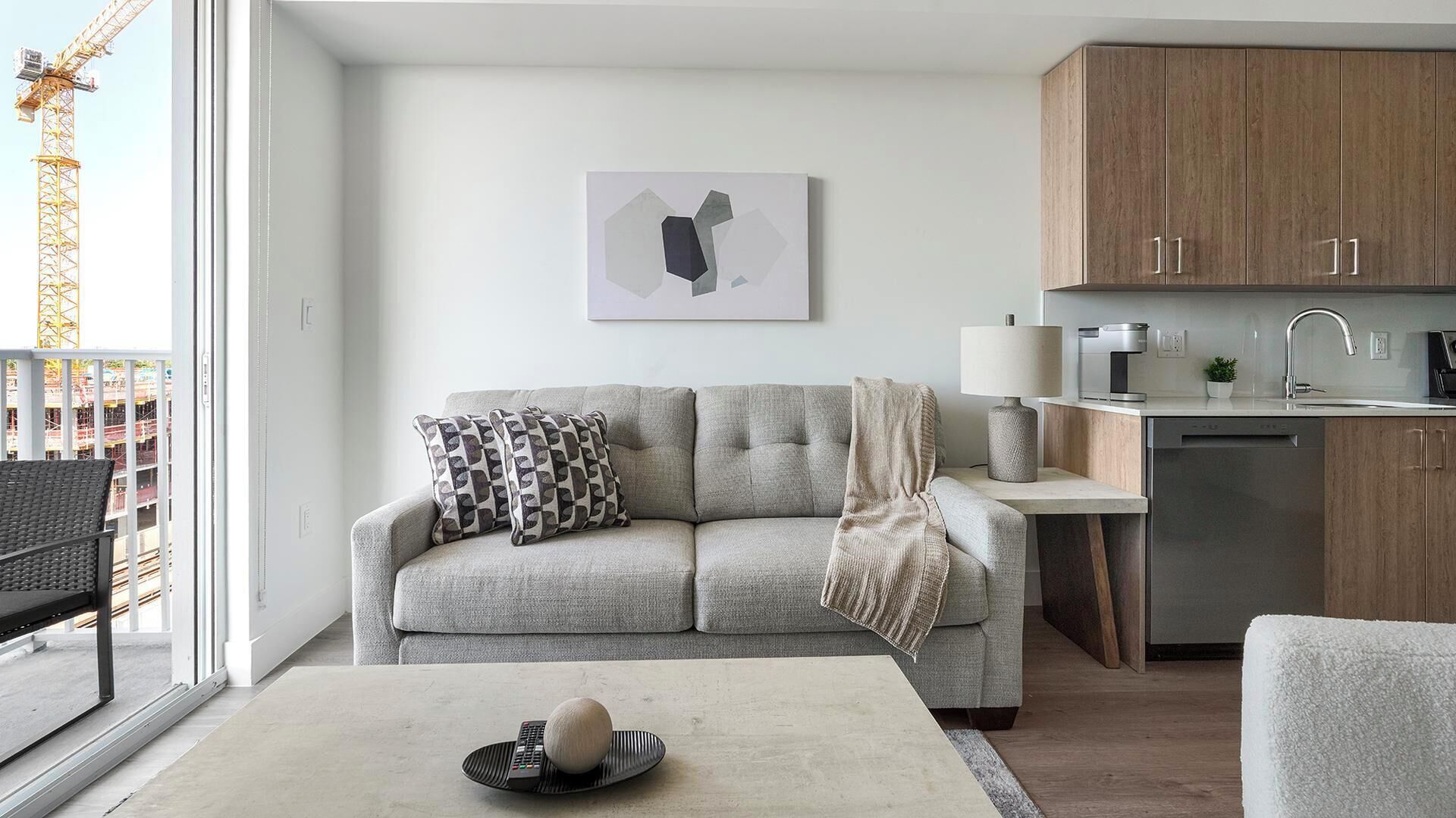 A modern living room with a sofa, a coffee table, and a kitchen area with cabinets and appliances.