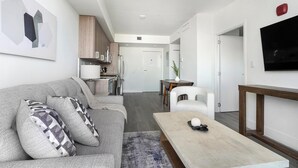 A modern living room with a grey sofa, a wooden coffee table, and a TV mounted on the wall.