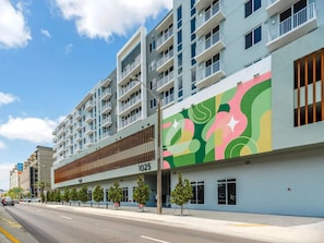 Un hôtel à plusieurs étages, doté d’une façade moderne, de balcons et d’une fresque murale aux couleurs vives.