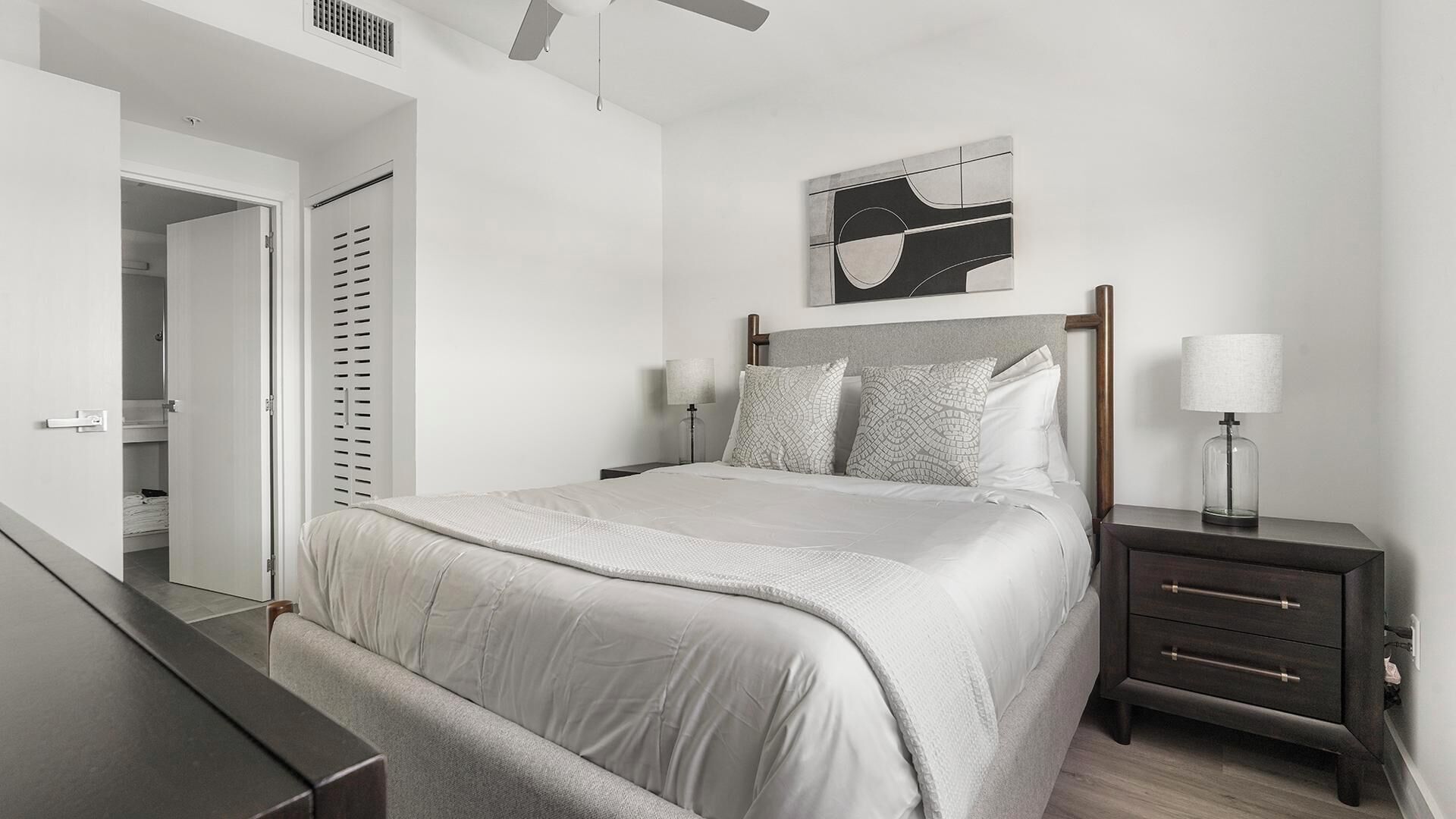 A modern bedroom with a bed, bedside tables, a lamp, and a ceiling fan.