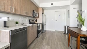 A modern kitchen with wooden cabinets, stainless steel appliances, and a dining area with a table and chairs.