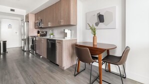 Eine moderne Küche mit Edelstahlgeräten, Holzschränken und einem Essbereich mit Tisch und Stühlen.