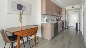 Une cuisine moderne avec des meubles en bois, des appareils électroménagers en acier inoxydable et un coin repas comprenant une table et des chaises en bois.