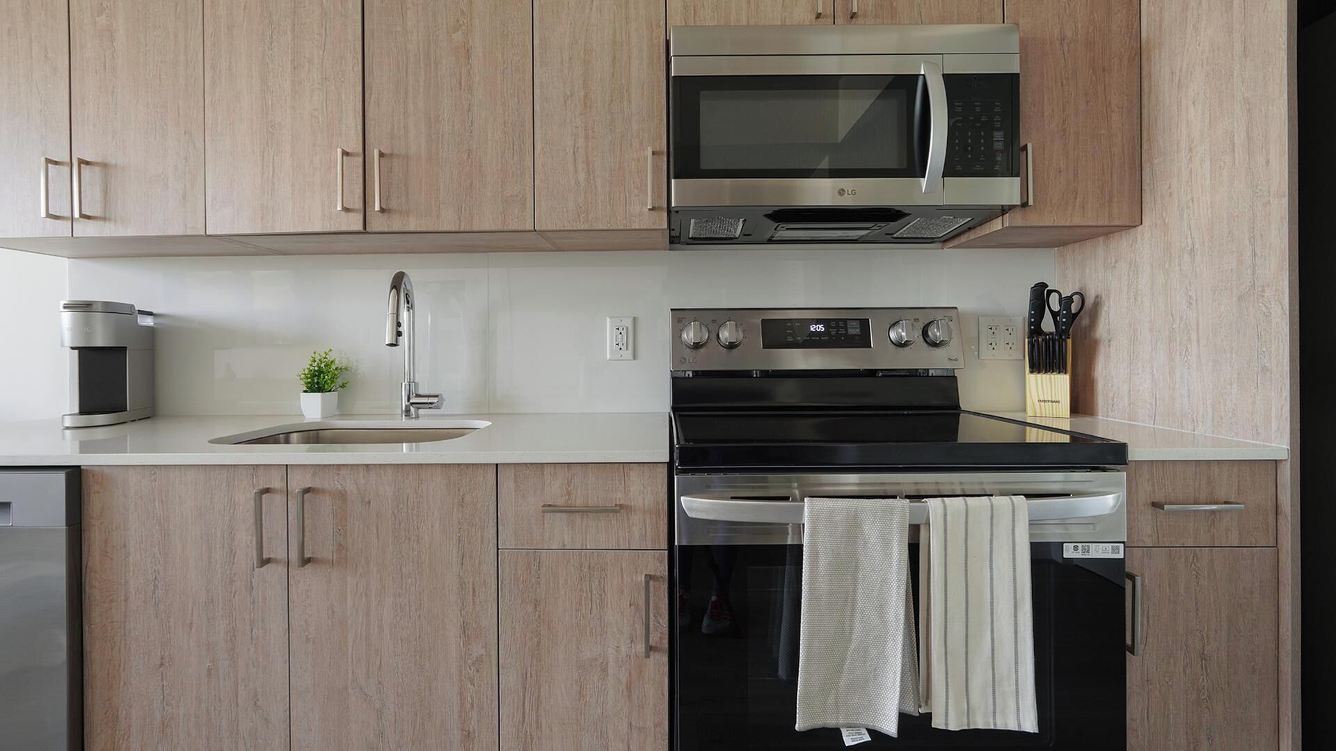 Une cuisine moderne dotée d’appareils électroménagers en acier inoxydable, d’un évier et de meubles de rangement en bois.