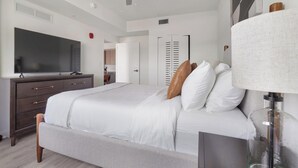Ein Schlafzimmer mit einem Bett, einem Schminktisch, einem Fernseher, einer Lampe und einem Kleiderschrank.