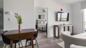 A modern bedroom with a bed, bedside table, and a ceiling fan. - Landing | Spectacular 1BD, Gym (Hialeah)