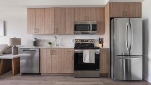 A modern kitchen with stainless steel appliances, wooden cabinets, and a built-in oven. - Landing | Stylish 1BD, Gym (Hialeah)