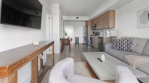 A modern living room with a sofa, coffee table, and TV. - Landing | Stunning 1BD, Gym (Hialeah)