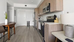 Una cocina moderna con electrodomésticos de acero inoxidable, armarios de madera y un comedor con mesa y sillas.